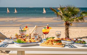 A beachside dining table with various dishes and drinks, overlooking the ocean with sailboats in the distance. - Cocon près de la Baule (Saint-André-Des-Eaux)