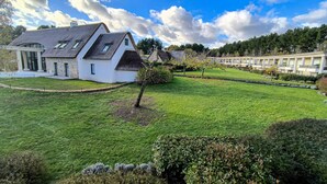 A modern house with a sloped roof, a well-maintained lawn, and a row of trees in the background. - Cocon près de la Baule (Saint-André-Des-Eaux)