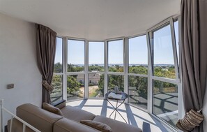 A corner room with a large bay window overlooking a residential area and a body of water. - Amazing home in Ploemeur with WiFi (Ploemeur)