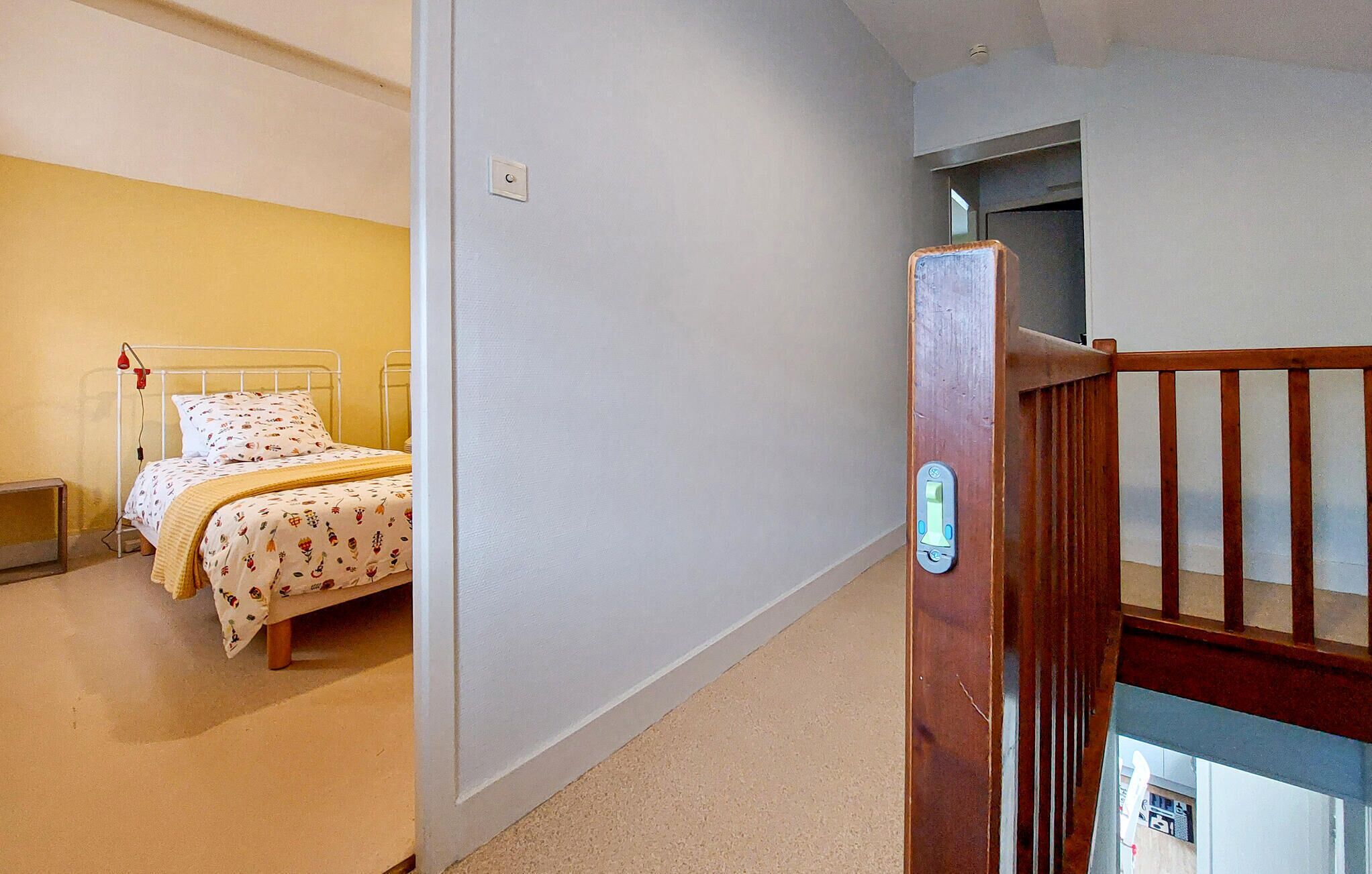 A bedroom with a bed, a bedside table, and a door with a handle.