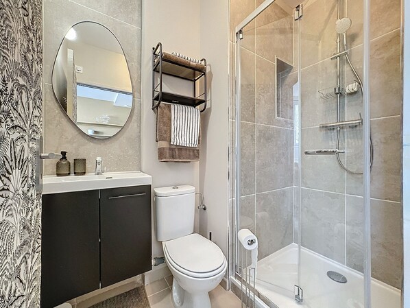 A modern bathroom with a toilet, sink, and shower. - SacresappartsLib (Reims)