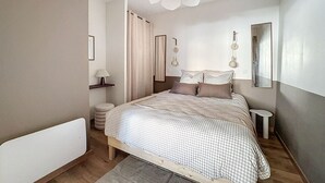 A bedroom with a bed, bedside tables, a ceiling fan, and a mirror. - SacresappartsLib (Reims)