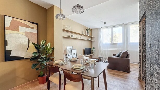 A dining area with a wooden table set for four, surrounded by chairs. There are hanging crystal pendant lights above the table. - SacresappartsLib (Reims)
