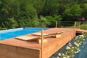 A wooden deck with a pool, surrounded by lush greenery. - Nature Escape Villa Pool (Montebelluna)
