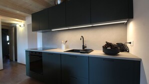 A modern kitchen with dark cabinets, a stainless steel sink, and a countertop.