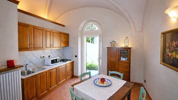 A kitchen with wooden cabinets, a stove, a sink, and a dining table with chairs.