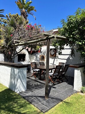 An outdoor patio with a pergola, a dining table with chairs, and a dartboard. - 2stay apartment Calla Bloubergstrand  (Cape Town)