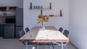 A modern kitchen with a wooden dining table, chairs, and a vase of dried flowers. - 2stay apartment Calla Bloubergstrand  (Cape Town)