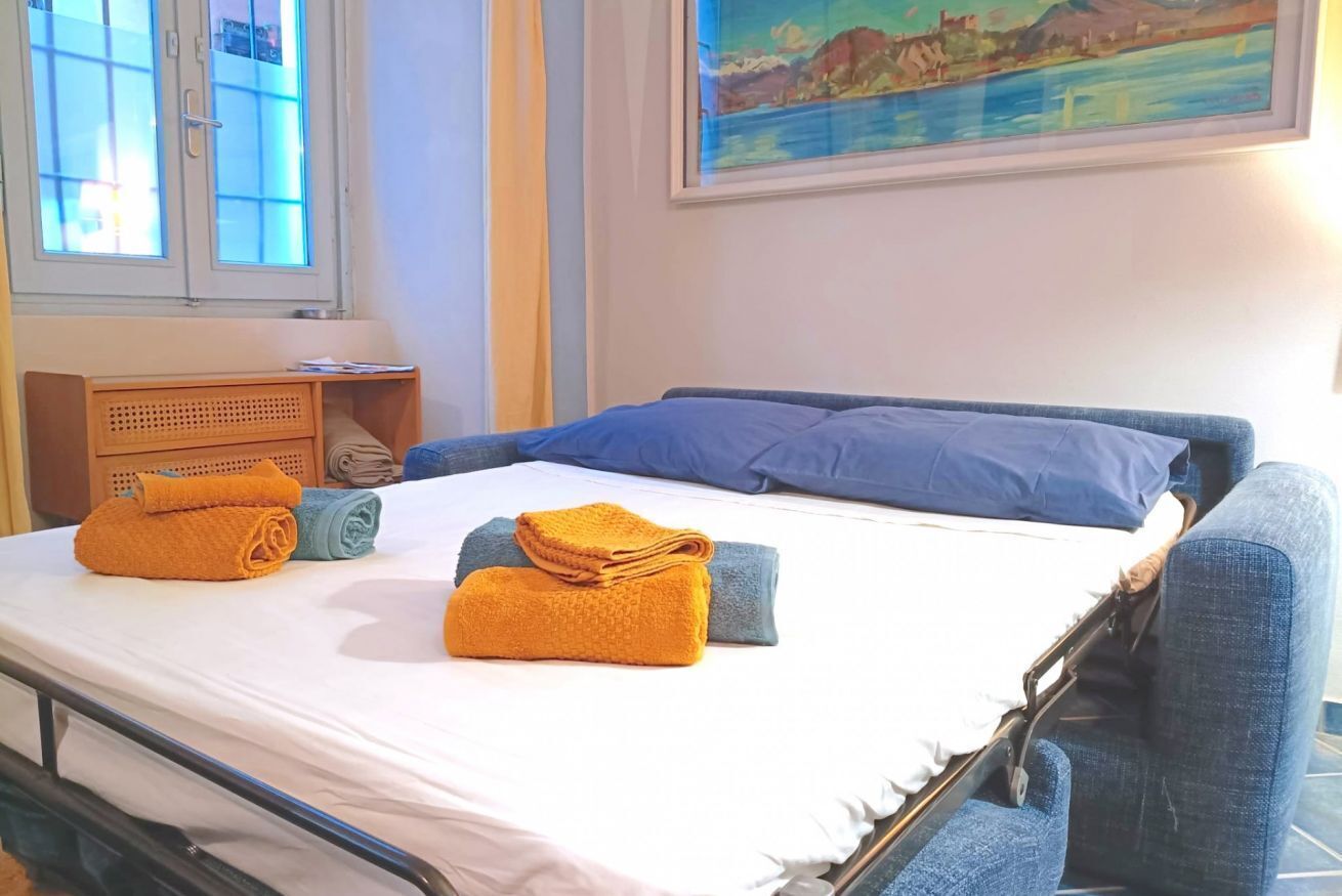 A bed with blue and orange towels, a wooden nightstand, and a painting of a landscape.