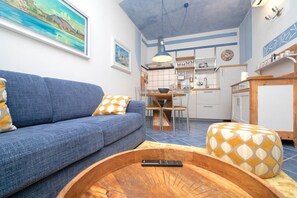 A living room with a sofa, a coffee table, a dining table, and a kitchen area. - Charming one-bedroom apartment, finely furnished, located on the ground floor of Via Pertossi in the historic centre of Arona.Casa Azzurra is a 52 sqm one-bedroom apartment with air conditioning, featuring a living room/kitchen area with a double sofa be (Arona)