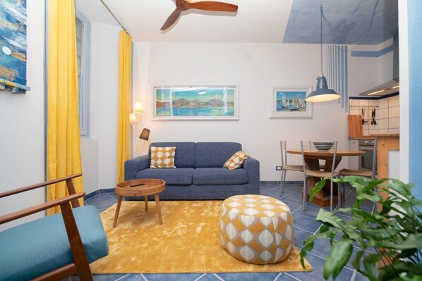 A living room with a sofa, a round ottoman, a coffee table, and a dining area with a table and chairs.
