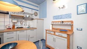 A compact kitchen with a wooden table, a blue bowl, a kettle, and a coffee machine. - Charming one-bedroom apartment, finely furnished, located on the ground floor of Via Pertossi in the historic centre of Arona.Casa Azzurra is a 52 sqm one-bedroom apartment with air conditioning, featuring a living room/kitchen area with a double sofa be (Arona)