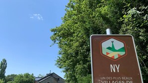 Une pancarte avec un logo et un texte en français, indiquant un village nommé NY dans la région de la Wallonie.