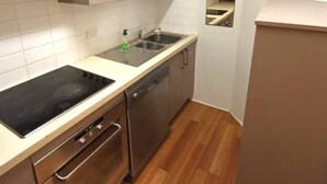 Une cuisine de taille réduite équipée d’un lave-vaisselle, d’un évier et d’une cuisinière.