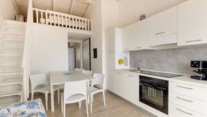 A modern kitchen with white cabinets, a built-in oven, and a dining area with a table and chairs. - Terrazza, air conditioning and post bus private (Paduledda)