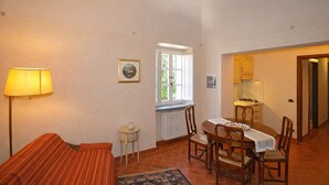 Ein gemütliches Zimmer mit Bett, einem kleinen Tisch, Stühlen, einer Lampe, einem Fenster und einer Küchenzeile.