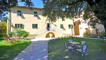 A building with a stone pathway leading to a courtyard with outdoor seating.