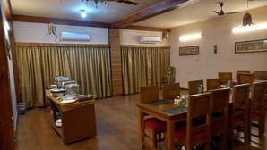 A dining area with wooden tables and chairs, air conditioning units, and curtains.