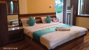 A neatly made bed with a wooden headboard, a bedside table with a lamp, and a window with curtains.