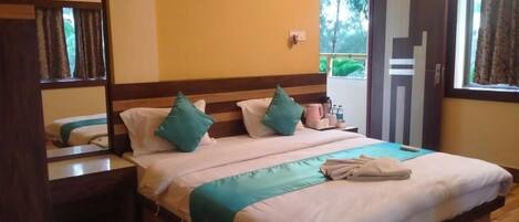 A neatly made bed with a wooden headboard, a bedside table with a lamp, and a window with curtains.