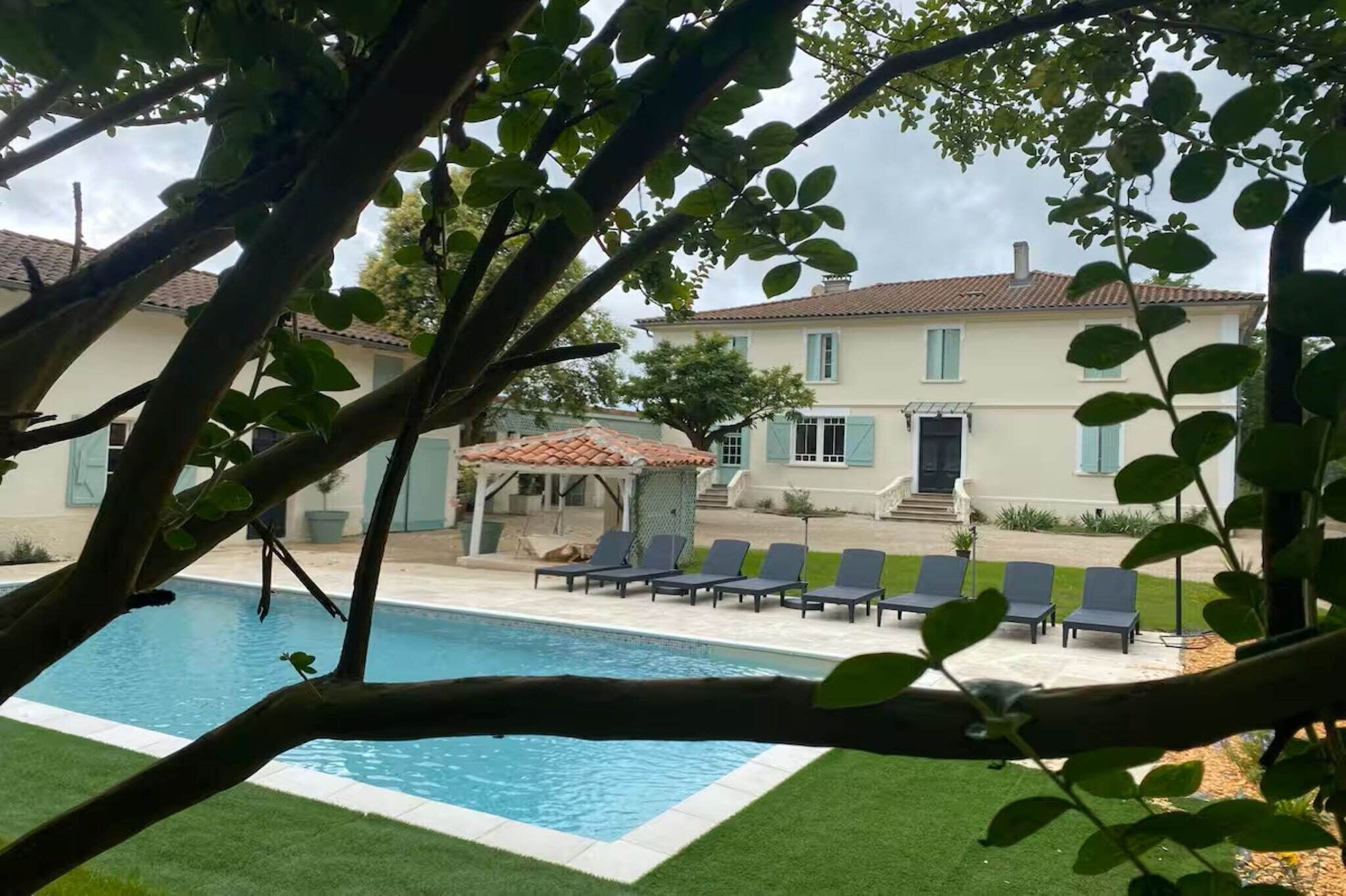 A pool area with lounge chairs and a gazebo.
