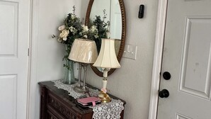 Un aparador de madera con dos lámparas, un espejo y un florero con flores.