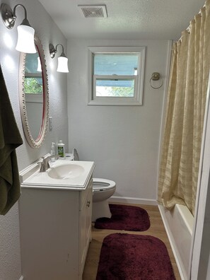 A bathroom with a white sink, a toilet, a window, and a shower curtain. - Delightful 2-bedroom house with AC in sunny Tampa (Tampa)