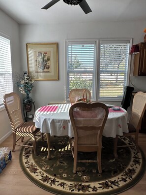 A dining area with a round table, four chairs, a ceiling fan, and a window with blinds. - Delightful 2-bedroom house with AC in sunny Tampa (Tampa)