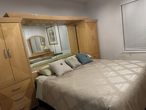 A bedroom with a bed, a wardrobe, a mirror, and a window with blinds. - Delightful 2-bedroom house with AC in sunny Tampa (Tampa)