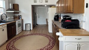 Una cocina con armarios de madera, extractor de acero inoxidable, refrigerador blanco y cafetera.