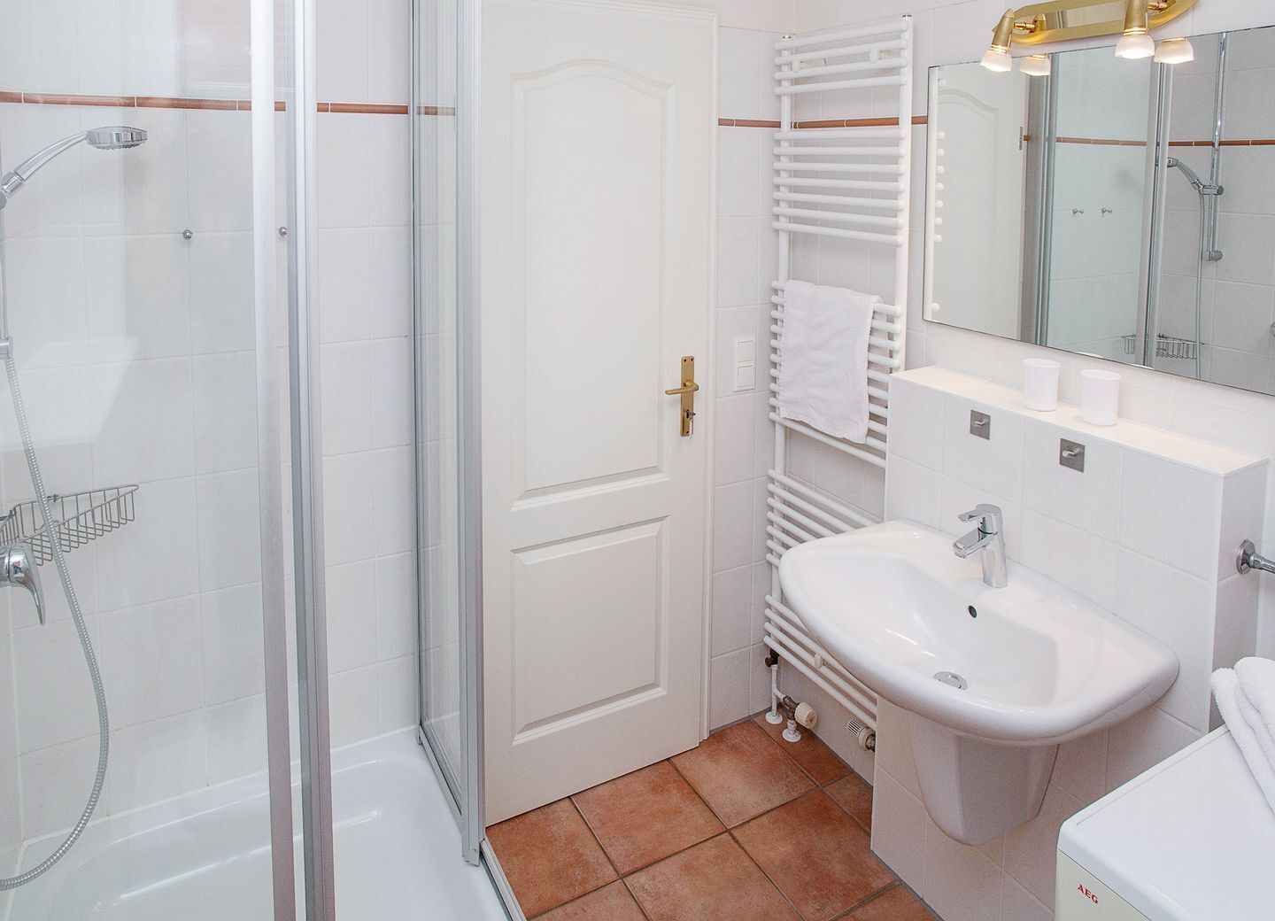 Un bagno con box doccia in vetro, un lavandino bianco e un portasciugamani.