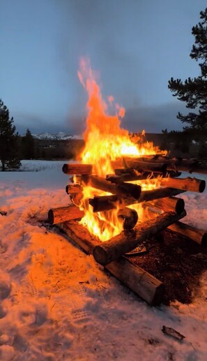 A campfire burning in a snowy outdoor setting. - Cabin #1 Charming 2-bedroom rustic cabin in Gould perfect for a getaway (Walden)