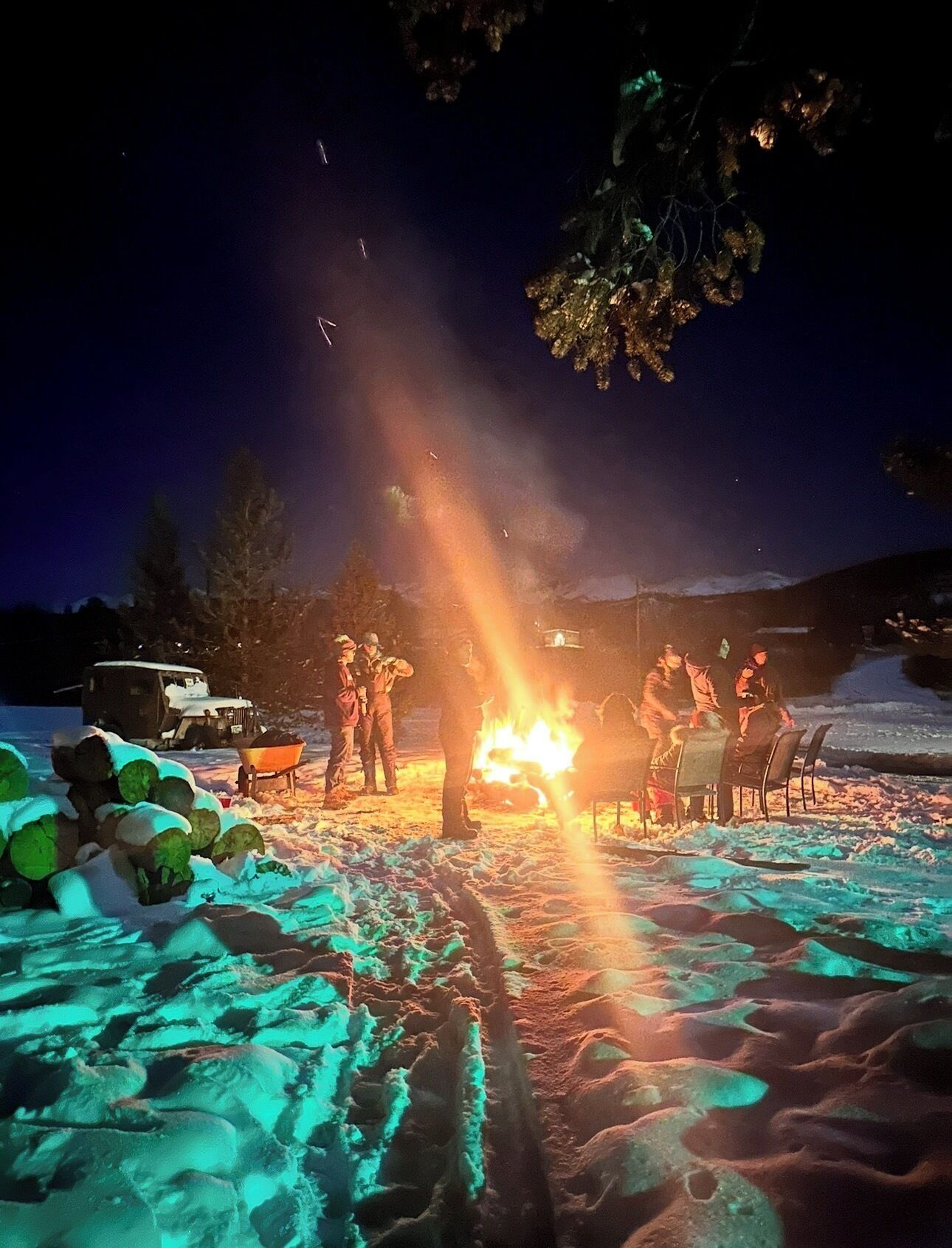 A group of people gathered around a campfire in a snowy outdoor setting.