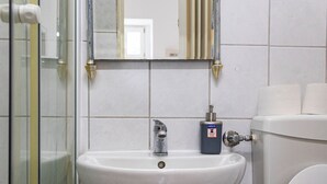 Kylpyhuone, jossa on valkoinen pesuallas, peili ja wc-istuin.