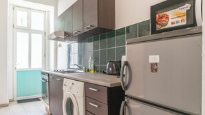 Moderni keittiö, jossa on pesukone, jääkaappi ja mikroaaltouuni.
