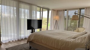 A bedroom with a large bed, a television, a chair, and a lamp. - The Sweet Escape – Premium villa with pool (Theux)