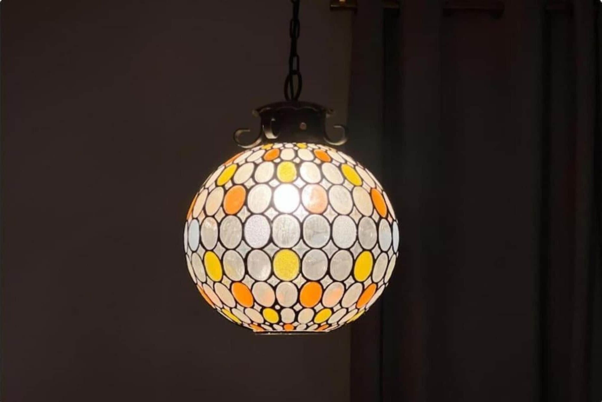 A spherical hanging light fixture with a mosaic pattern.