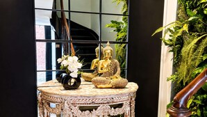 Une table ronde ornée d’une statue de Bouddha et d’un vase de fleurs.