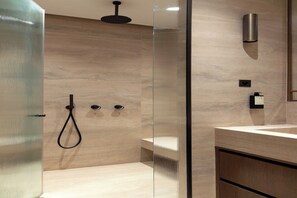 A modern bathroom with a glass shower enclosure, a handheld showerhead, a wall-mounted light, and a visible toilet paper dispenser. - Luxury A/C Apt - 10P/4BDR - Arc de Triomphe (Paris)