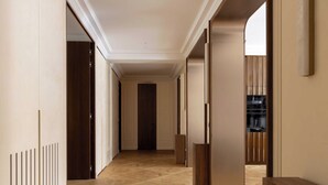 A hallway with a herringbone floor, wooden doors, and a view into a room with a kitchen area. - Luxury A/C Apt - 10P/4BDR - Arc de Triomphe (Paris)