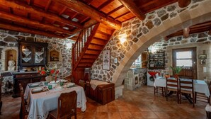 Un comedor rústico con paredes de piedra, vigas de madera y una escalera de piedra.