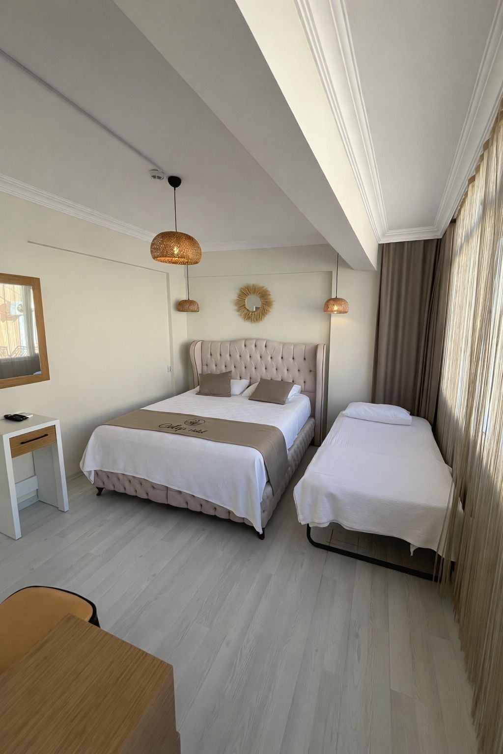 Una habitación de hotel con una cama grande, una cama más pequeña, un escritorio y una silla.