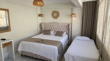 Una habitación de hotel con una cama grande, una cama más pequeña, un escritorio y una silla.