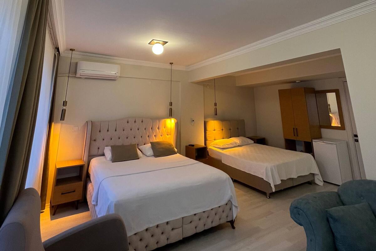Una habitación de hotel con dos camas, un sofá, un escritorio y un espejo.