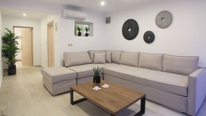 A modern living room with a sectional sofa, a wooden coffee table, and decorative wall plates. - Stone Crafted Luxury Villas - Villa Artemis (Nikiana)