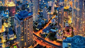 A cityscape at dusk with illuminated buildings and a prominent roundabout. - Casa Amor (Bangkok)