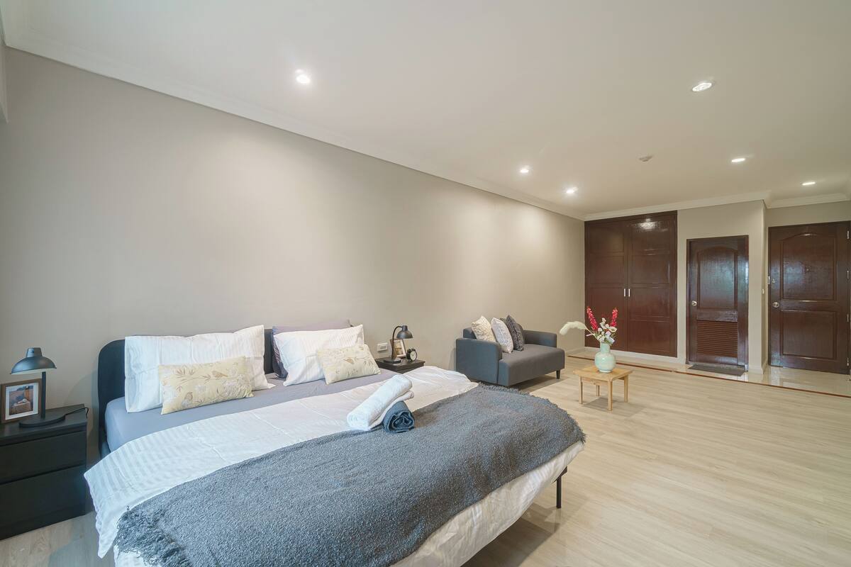 A modern bedroom with a large bed, a sofa, a small table, and a nightstand.