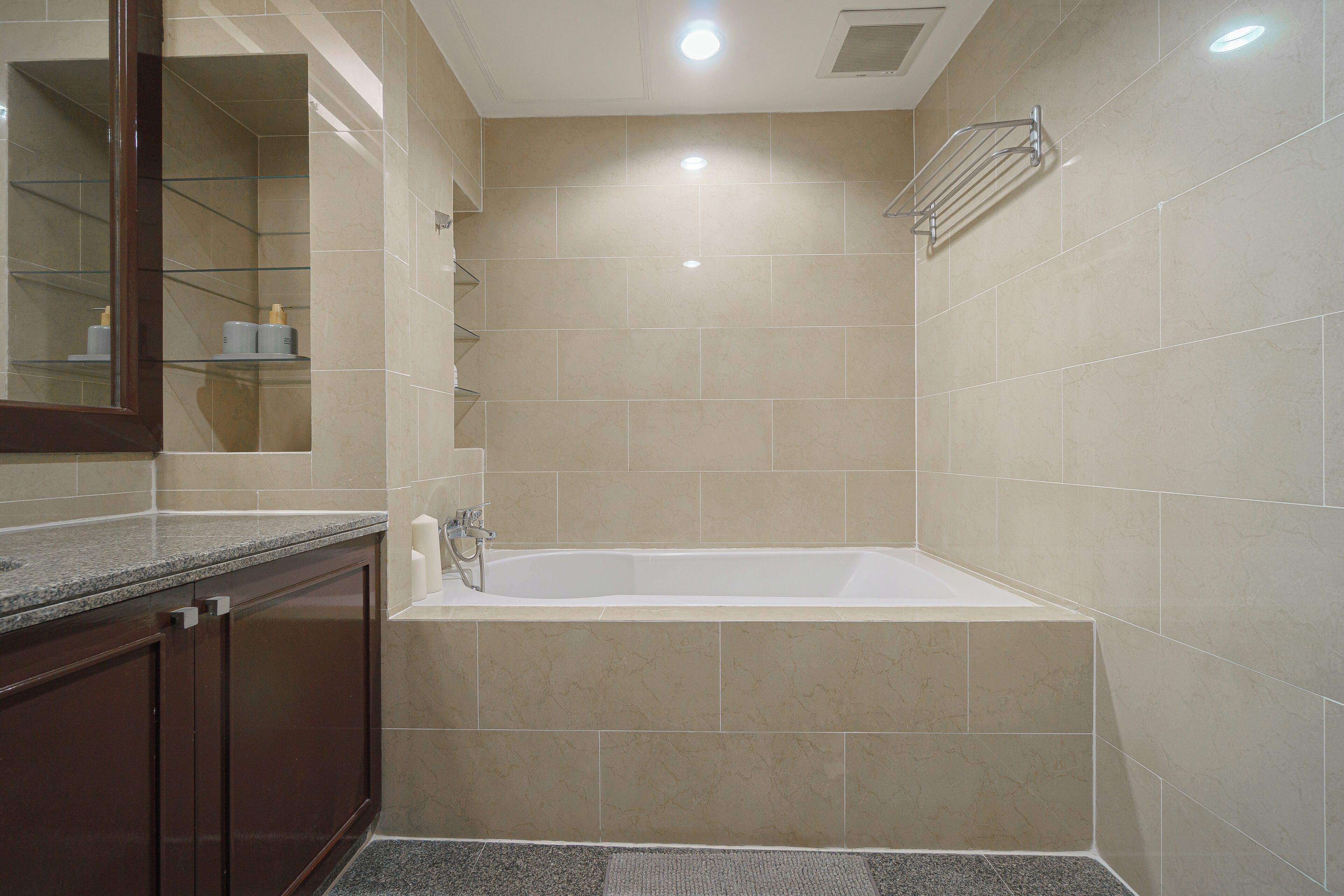 A modern bathroom with a bathtub, a glass shower enclosure, and a marble-tiled wall.
