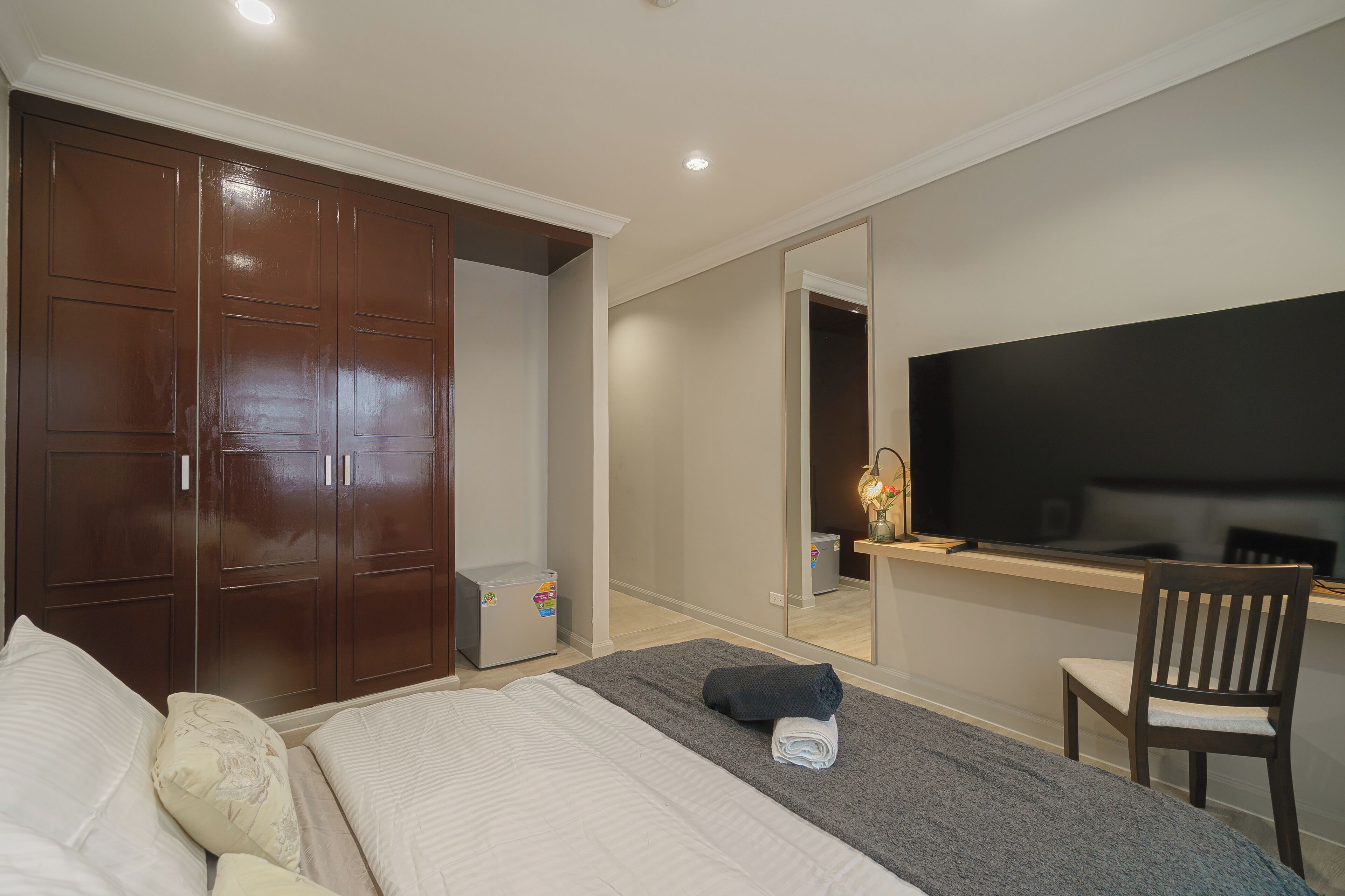 Une chambre à coucher comprenant un lit, une armoire, un bureau avec une chaise et un téléviseur.