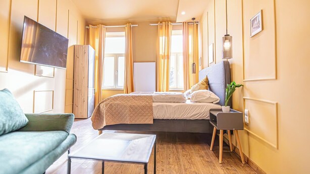 Een moderne hotelkamer met een bed, een slaapbank, een televisie en een bijzettafeltje.